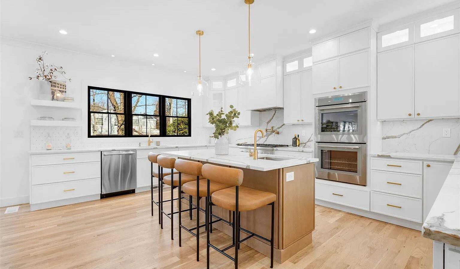 White kitchen with wood island, gold pendants and double wall ovens