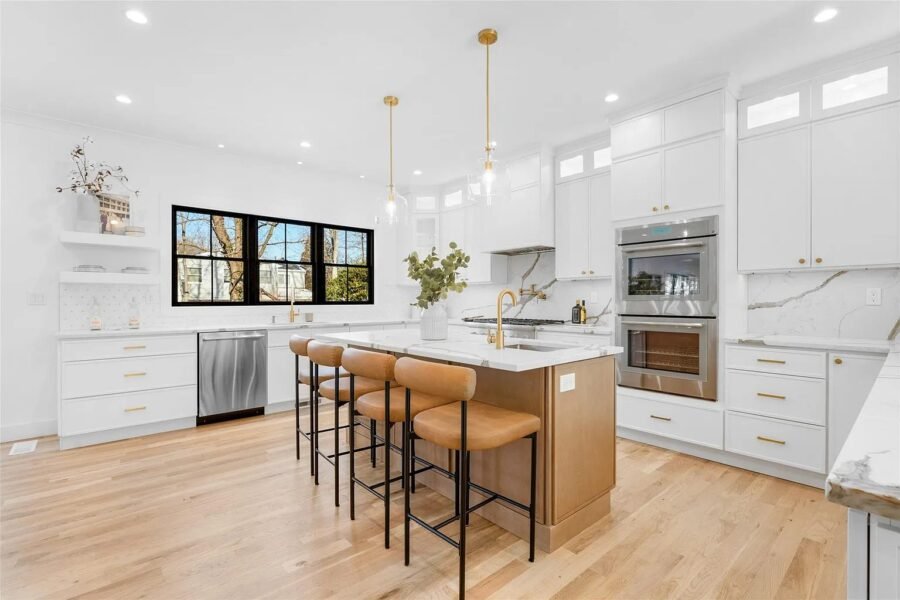 White kitchen with wood island, gold pendants and double wall ovens