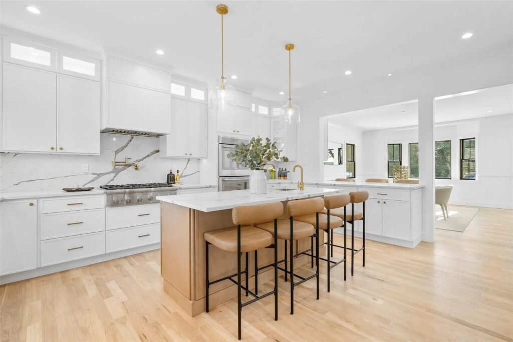 Kitchen with white cabinets and wood island with counter stools