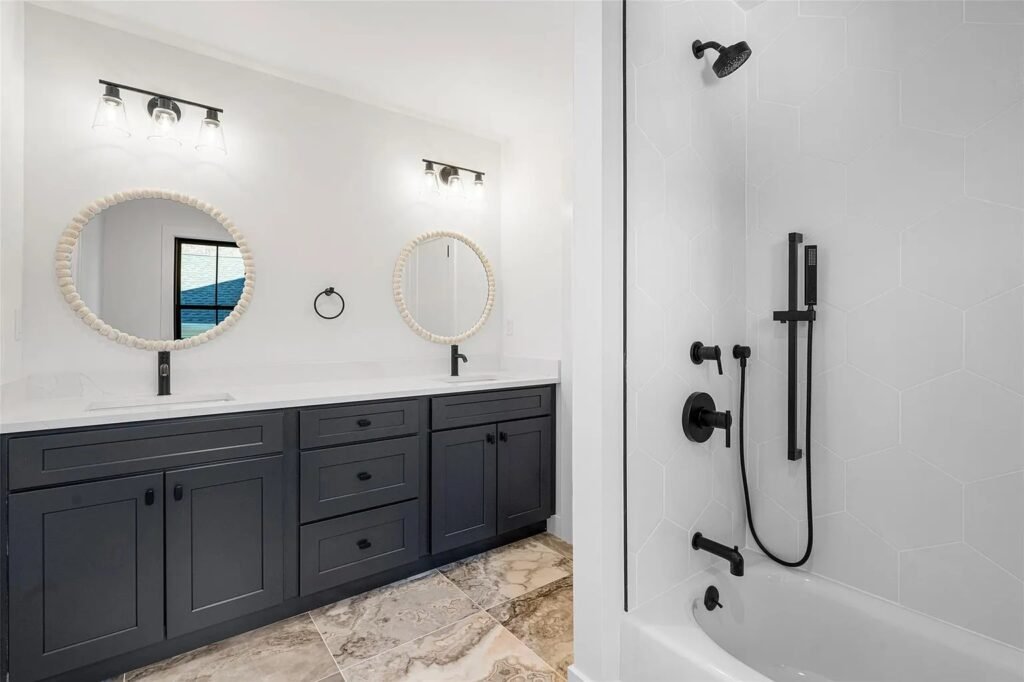 Bathroom with dark vanity, marble floor and black fixtures