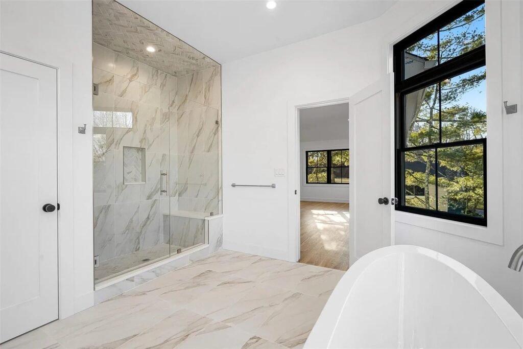 Walk-in marble shower beside a freestanding tub