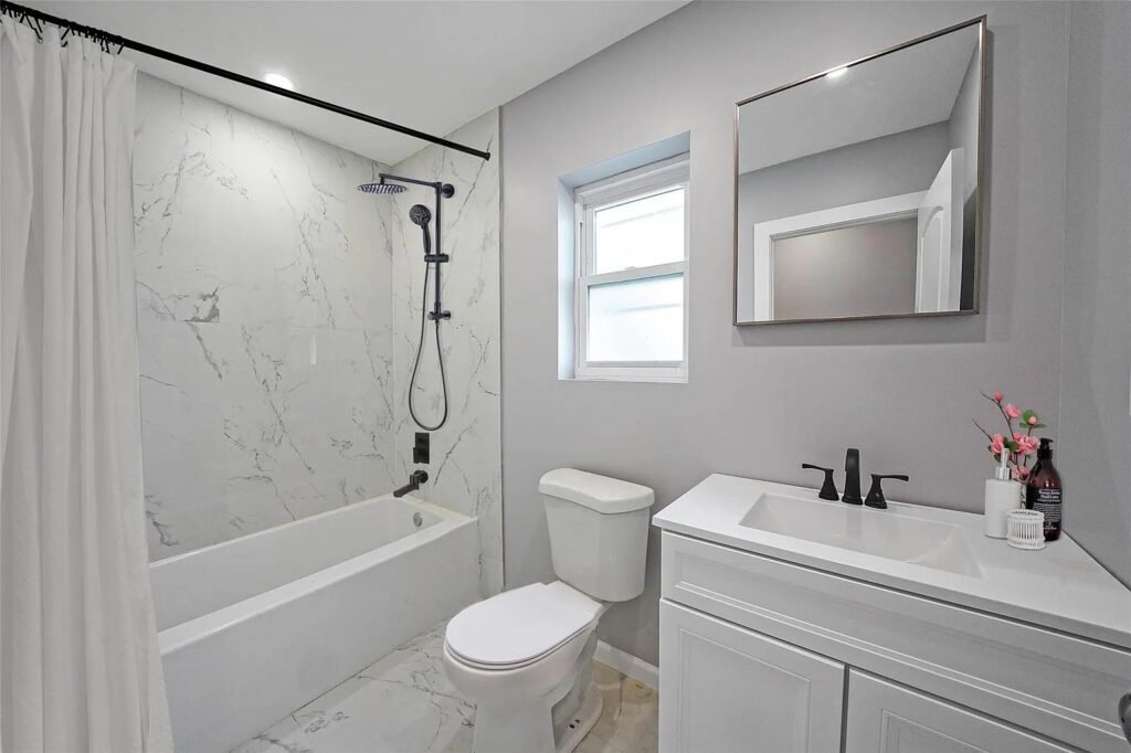 Bathroom with marble look tub shower and black fixtures