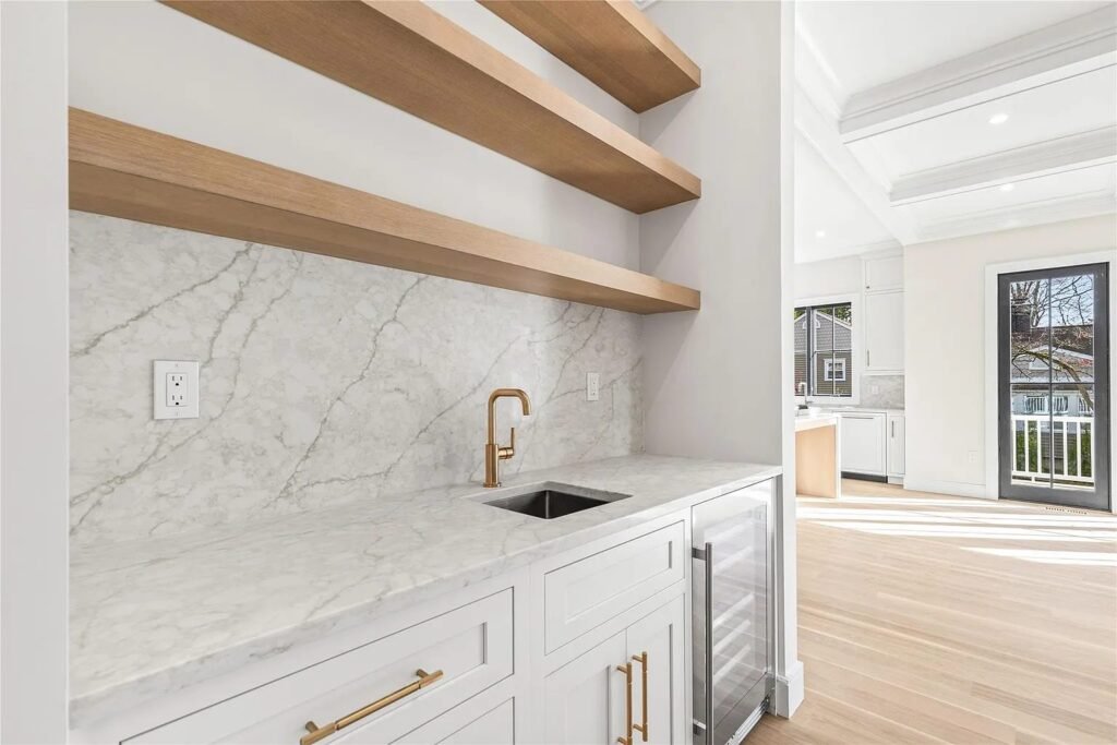 Marble backsplash with floating wood shelves and gold faucet