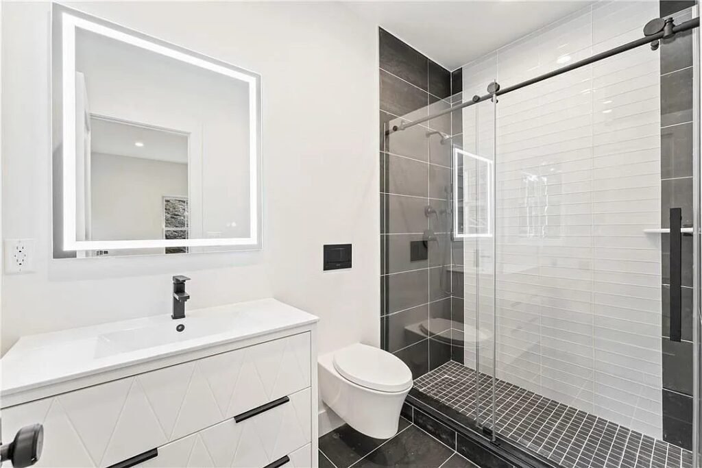 Bathroom with sliding glass shower door and lighted mirror