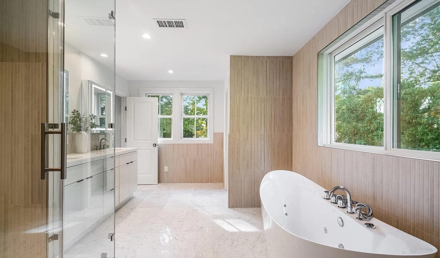 Bathroom with freestanding tub, glass shower and wood paneled wall