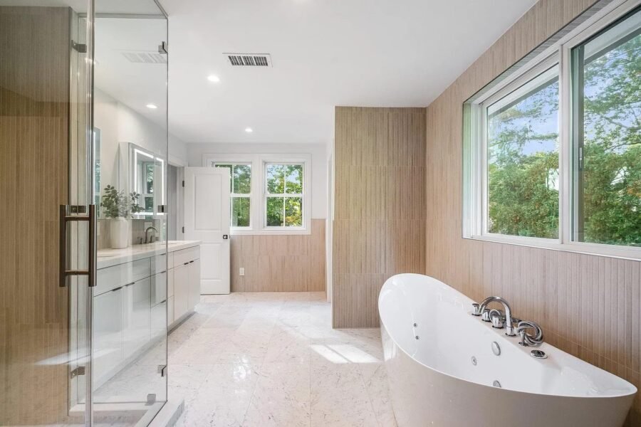 Bathroom with freestanding tub, glass shower and wood paneled wall