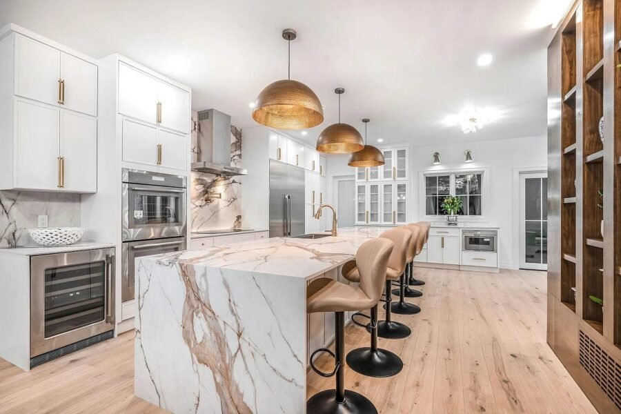 Kitchen with marble waterfall island, brass pendant lights and white cabinets