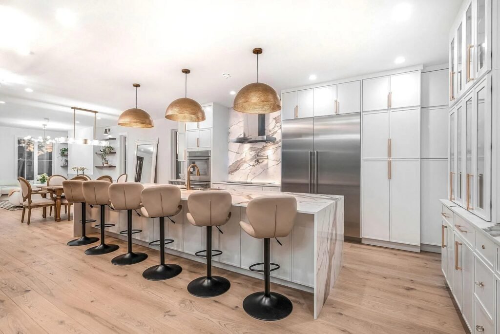 Kitchen island with brass pendants and tall stainless appliances