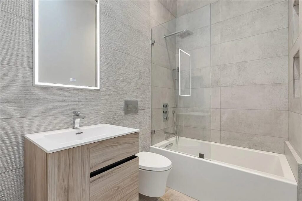 Bathroom with wood vanity, large mirror and tub shower