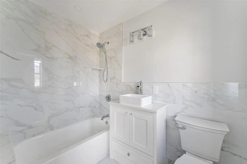 Bathroom with marble look tile and tub shower